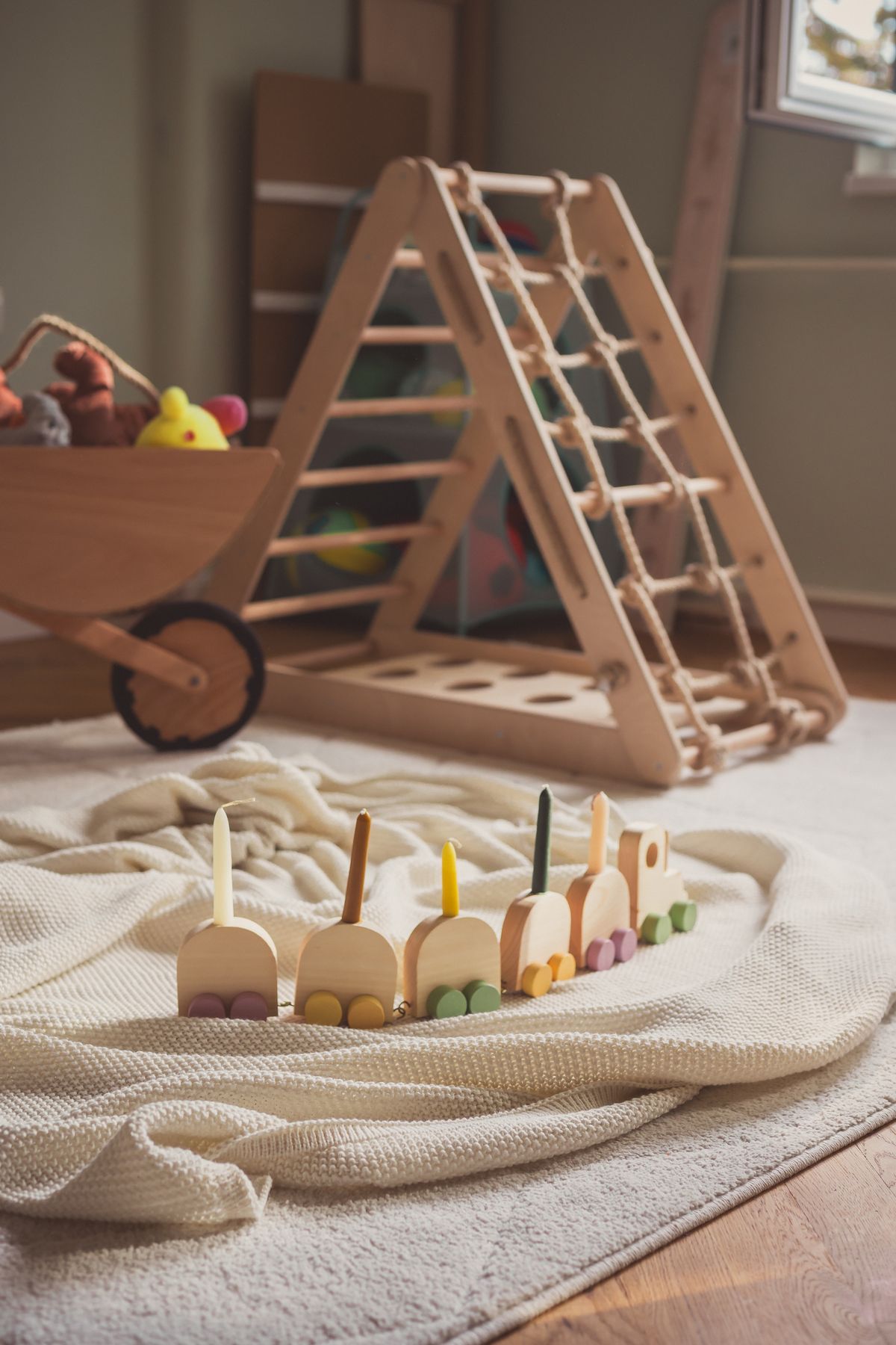A child's sunlit play space with wooden toys and a low climbing frame