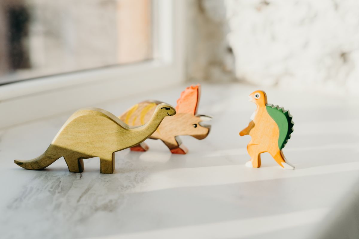 Wooden animal figures lined up on a windowsill in warm light
