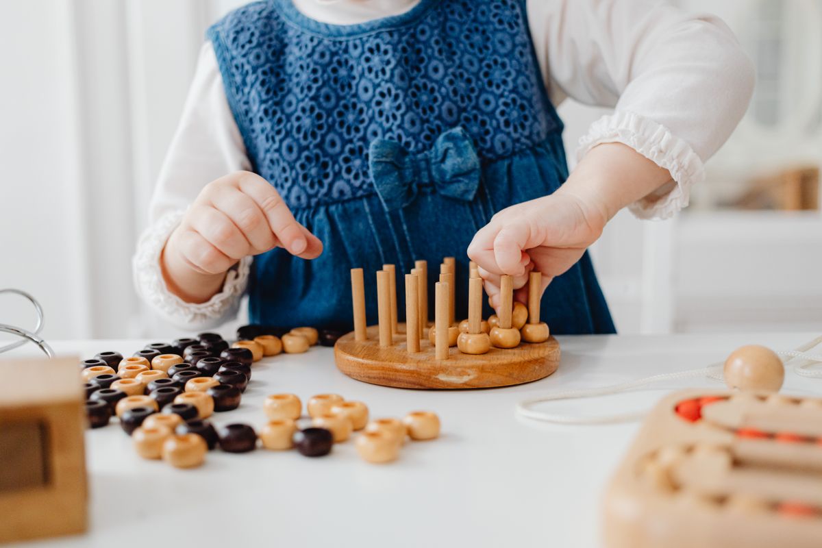 A child's hands working quietly with a wooden sorting material