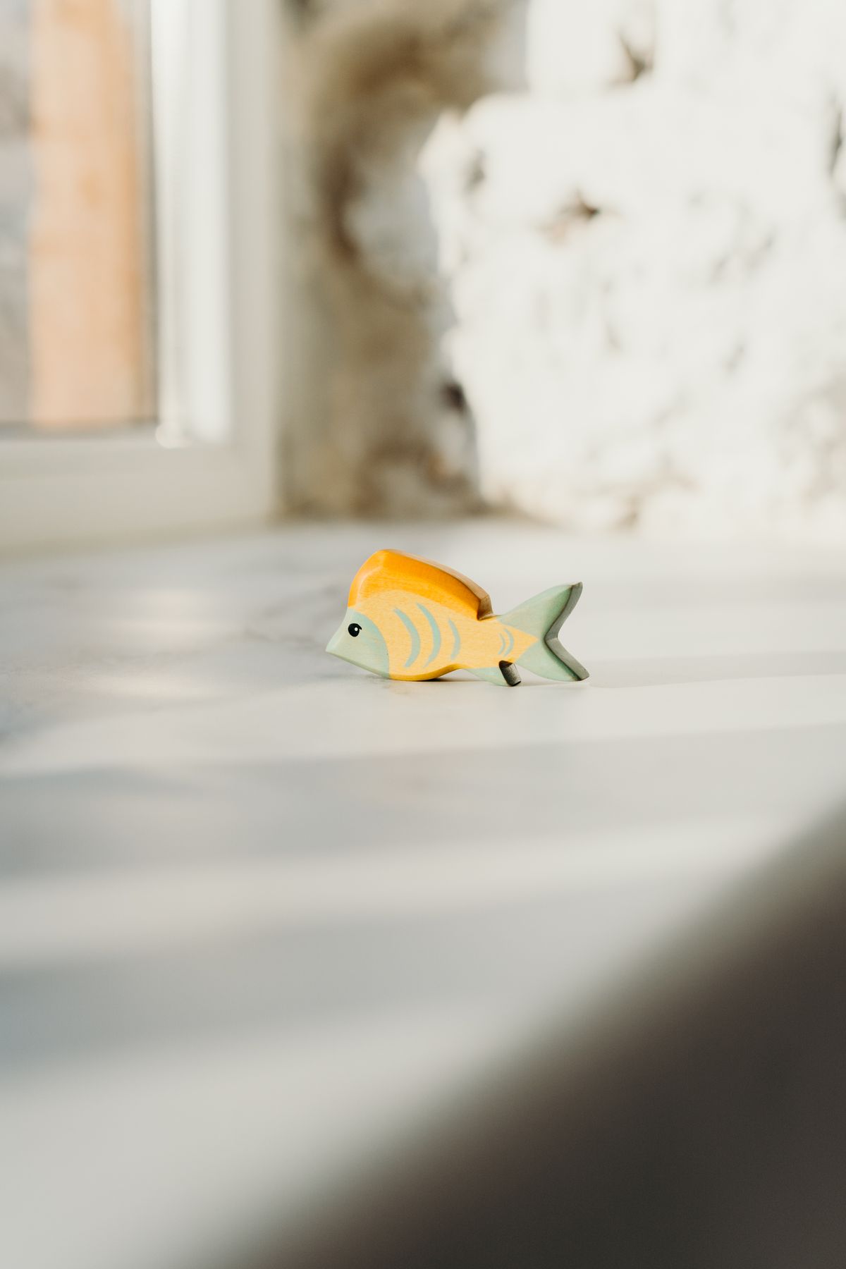 A wooden fish toy in soft natural light, casting gentle shadows